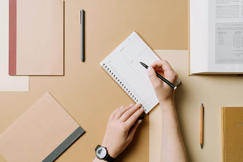 Una persona che scrive su un taccuino in un ambiente di lavoro luminoso e moderno